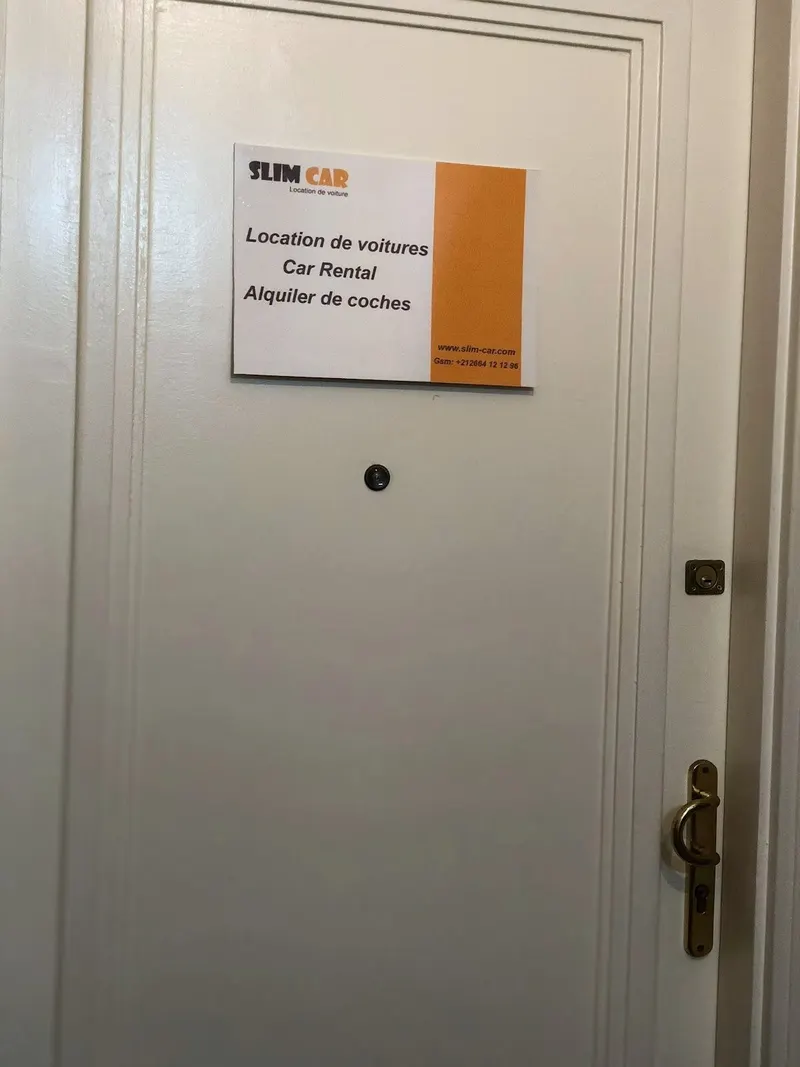 La porte de l’agence et sa plaque « Slim Car – Location de voitures / Car Rental / Alquiler de coches »